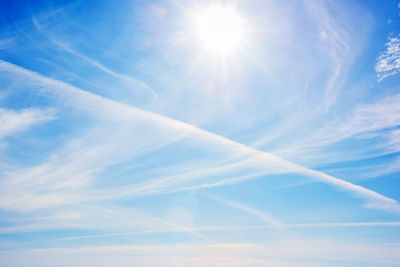 Low angle view of sunlight streaming through clouds