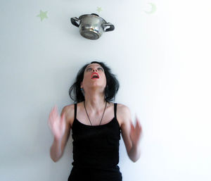 Stew pot falling on young woman standing against white background