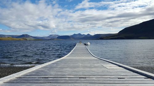 Boardwalk by lake against sky