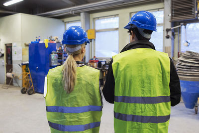 Rear view of male and female workers in protective workwear at factory