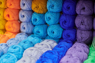 Yarns or balls of wool on shelves in store for knitting and needlework, close up. haberdashery