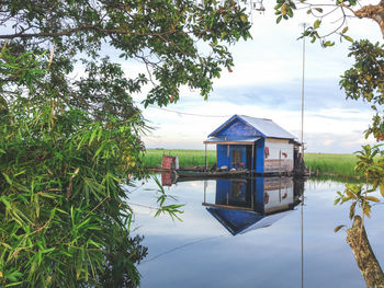 House by lake against sky