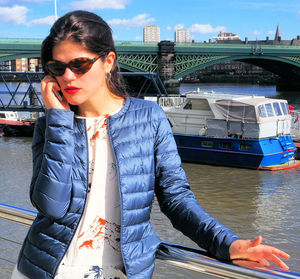 Woman talking on smart phone while standing by railing in boat