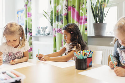 Female students drawing at table in classroom