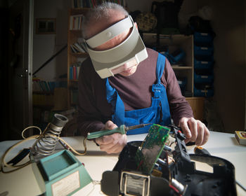 Man repairing circuit board at table