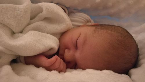 Close-up of newborn baby boy sleeping on bed