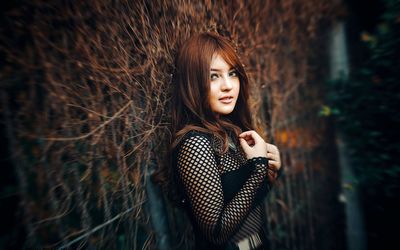 Portrait of young woman standing against trees