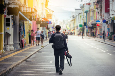 Rear view of man walking on street in city