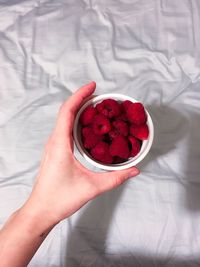 Close-up of hand holding strawberries in bowl