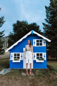 Woman standing by building against blue sky