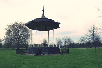 Gazebo on field by building against sky