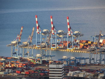 Cranes at harbor against city