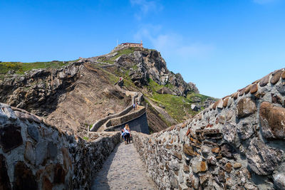 Rear view of people walking on fortified wall