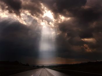 Storm clouds over road during sunset