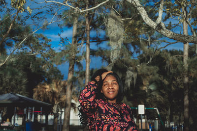 Portrait of smiling young woman standing against trees in winter