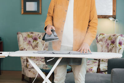 Young man at home ironing clothes, hot and evaporation