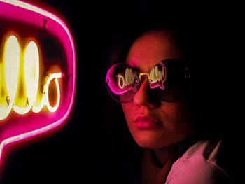 Close-up of woman wearing sunglasses against black background