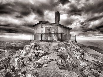 Abandoned built structure against cloudy sky