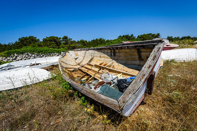 Abandoned boats on field against clear blue sky during sunny day