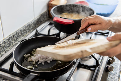 Grandma hands frying onion in a pan.