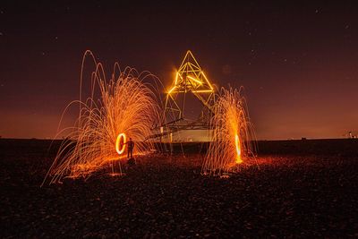 Illuminated light trails on field against sky at night