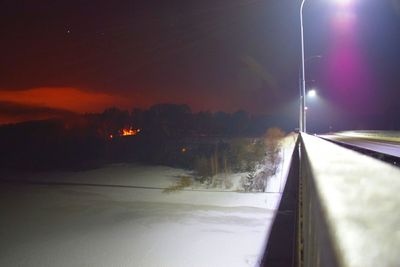 Road by trees against sky at night during winter