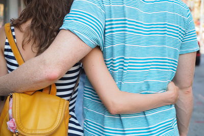 Midsection of young couple embracing on street