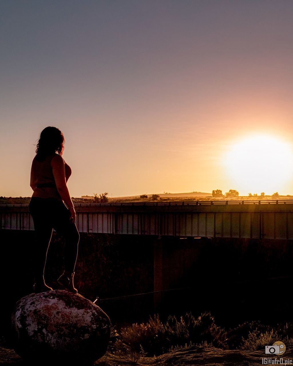 sky, one person, sunset, evening, nature, adult, water, full length, lifestyles, side view, women, person, sunlight, silhouette, reflection, horizon, dusk, architecture, beauty in nature, standing, tranquility, young adult, copy space, leisure activity, outdoors, sea, backlighting, clothing, solitude, built structure