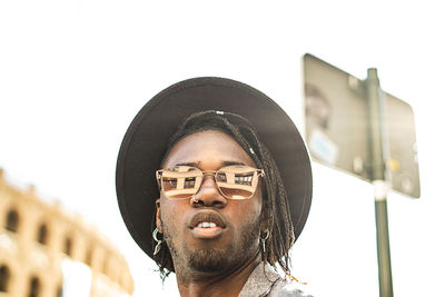 Close-up of young man standing in city against sky