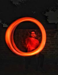 Portrait of young man standing against orange wall