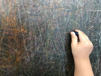 Cropped hand of child drawing on blackboard