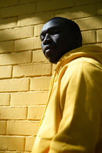 Low angle portrait of man standing against wall