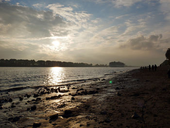 View of calm beach against cloudy sky