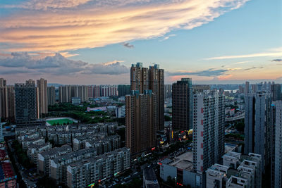 High angle view of modern buildings in city against sky during sunset