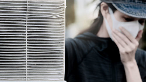 Woman wearing gas mask by blinds