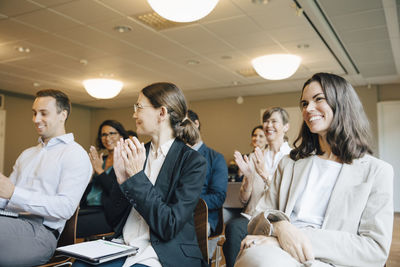 Smiling male and female clapping while sitting in office workshop