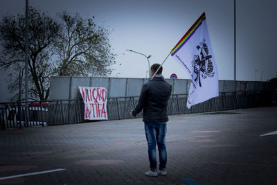 Full length rear view of man standing against sky in city