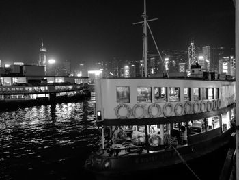 Illuminated pier over river in city against sky at night