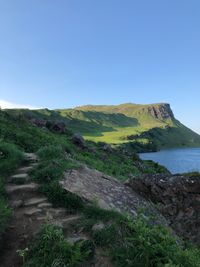 Scenic view of land and sea against clear blue sky