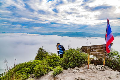 Man by thai flag pohotographing cloudscape