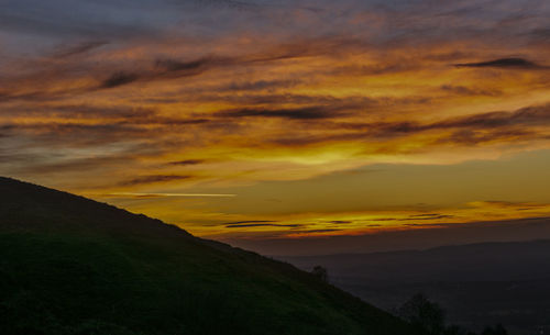 Scenic view of dramatic sky over silhouette landscape