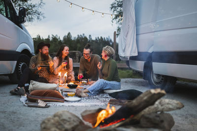 Smiling male and female friends spending leisure time by motor home