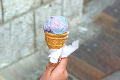 Holding fresh waffle cone with raspberry ice cream