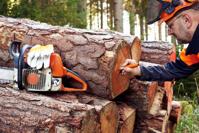 Professional lumberjack with protective workwear and chainsaw working in a forest