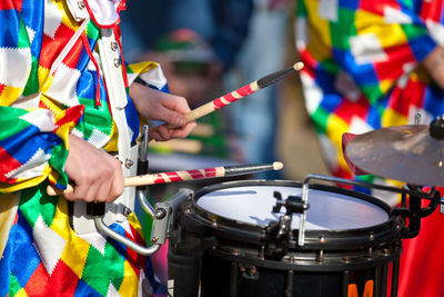 Midsection of drummer playing drum during carnival