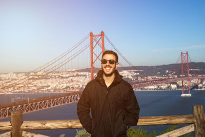 Happy mid adult man wearing sunglasses standing against golden gate bridge