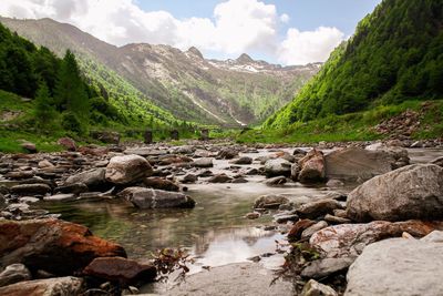 River flowing by mountains against sky