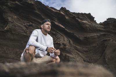 Young man sitting on rock