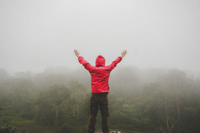 Rear view of man standing on mountain during foggy weather