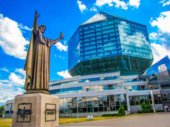 Low angle view of statue against building in city against sky